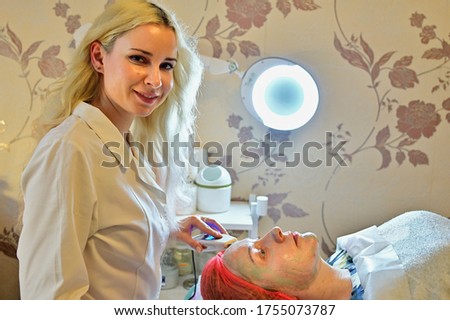 Beautician in the spa salon does massage device with mask. Photo of the face of a woman patient.