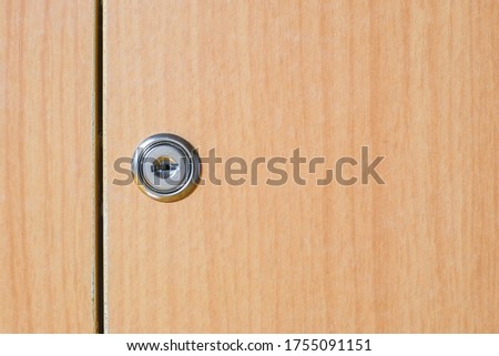 Steel keyhole lock of the brown wooden cabinet drawer close-up. Royalty-Free Stock Photo #1755091151