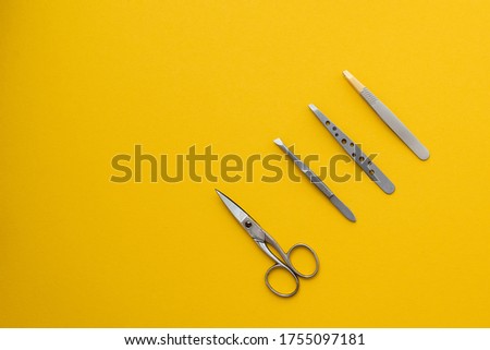 Tweezers on a yellow background, manicure scissors and tweezers on a yellow background, manicure scissors