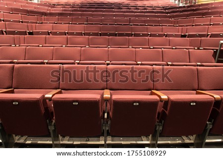 Photo of an empty theatre or cinema showing rows of red retractable seats