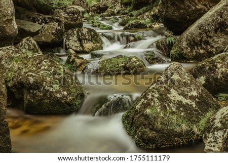 Waterfall photo. Long exposure photo of flowing water. Motion blur water in a mountain creek in a deep forest. Hiking in a nature reserve.Fresh clean cold water scene.Stones covered with moss.