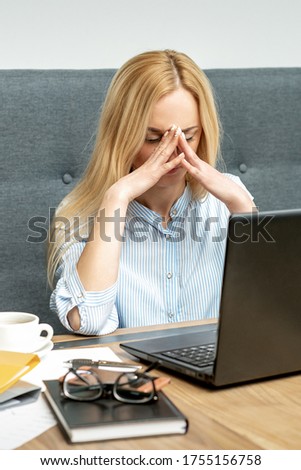 Tired young business woman sitting in front of laptop at office.
