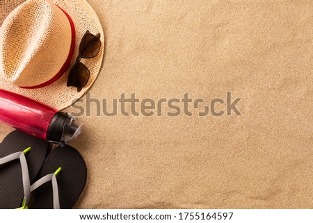 Beautiful summer holiday beach background with straw hat and sunglasses on sand background, top view with copy space