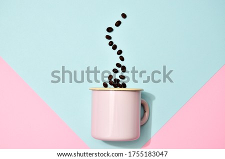 Pink enameled mug with coffee beans on colorful background. Flat lay photo with trendy pastel colors