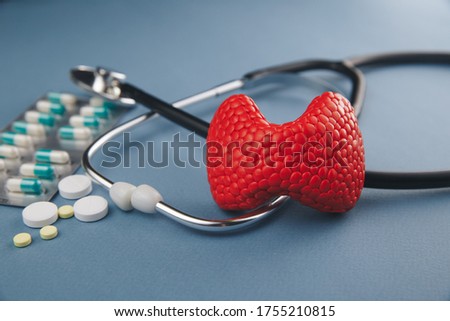 Thyroid treatment picture concept. Red gland and stethoscope with medicines, health care.