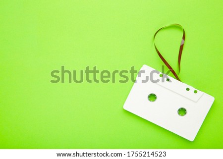One old white cassette on a green background. Music day, top view