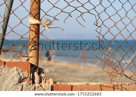 A selective focus shot of broken bared wire with a seashore background