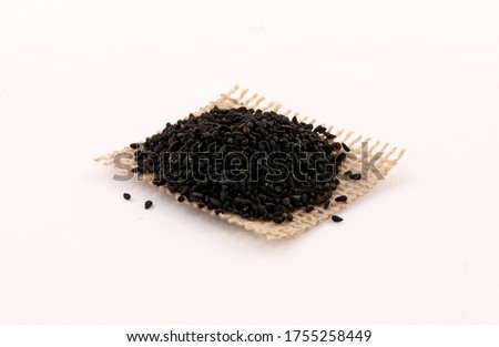 Black seed on a piece of burlap and wooden spoon isolated on white background Royalty-Free Stock Photo #1755258449