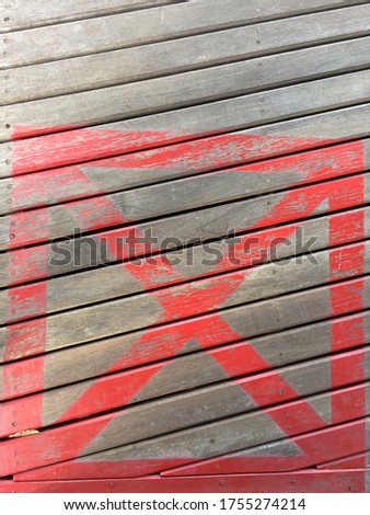 The red symbol picture of a cross in a square frame and wooden background