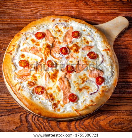 Delicious round pizza on a wooden stand on the table