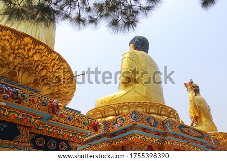 Back view of three large gold colored Buddha statues sitting in Lotus position (Padmasana) in Amideva Buddha Park (also known as Buddha Garden) located in the western part of Kathmandu city, Nepal.