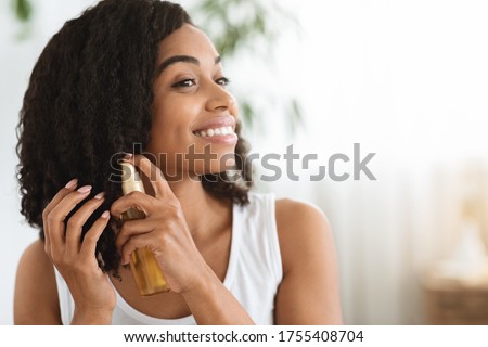 Hair Care. Happy Afro Woman Using Oil For Split Ends While Getting Ready At Home, Closeup Image With Copy Space Royalty-Free Stock Photo #1755408704