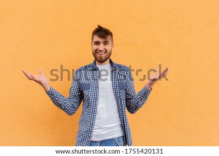 the Happy man makes a hand gesture against the backdrop of an orange wall