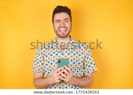 Portrait of handsome caucasian man wearing hawaiian shirt taking a selfie isolated over yellow background, celebrating success