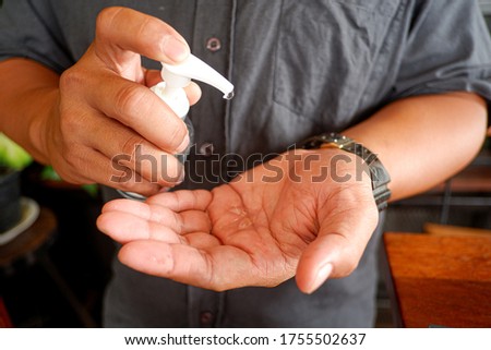 Cropped shot view of mans' hand use the alcohol gel sanitizer. Royalty-Free Stock Photo #1755502637