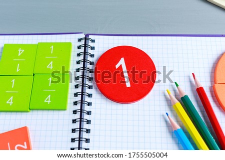 Close up of Multicolored math fractions on the open notepad on gray wooden table. Interesting math for kids background. Education, back to school concept	