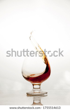 A splash of cognac in the glass on a white background