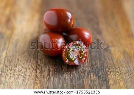 dark red brown tomato and whole vegetables on wooden background