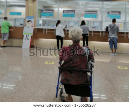 The blurred abstract background of the patients sitting on a wheelchair and the patients standing at the hospital were spaced by people to prevent the spread of virus Covid-19.