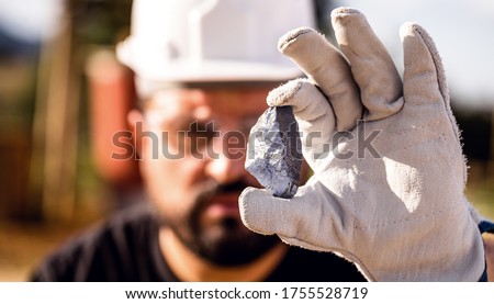 miner man holding a silver stone, point focus. Gemstone mining concept. Royalty-Free Stock Photo #1755528719