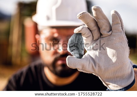 crude nugget of silver stone, manganese or palladium. Mining man holding ore in his hands. Spot focus. Royalty-Free Stock Photo #1755528722