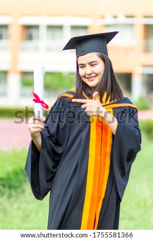 Graduation girl raises her hand to celebrate her graduation, complete with a diploma and her sense of pride and happiness.