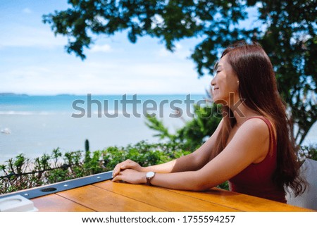 A beautiful young asian woman sitting and looking at the sea and blue sky 