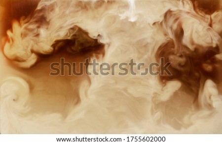 Closeup process of making latte, cappuccino, pouring milk, cream into transparent glass cup with coffee. Abstract brown background with light stains, explosion. Mixing of liquids. Hot caffeine drinks.