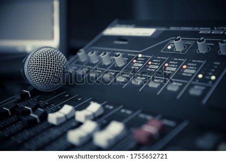 Close-up microphone on sound mixer equipment for recording, editing, and sound system control concept.