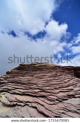 red slate against a blue sky with white clouds behind