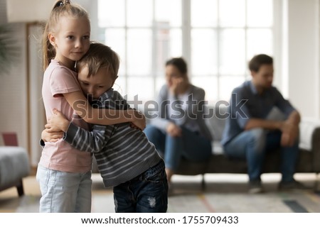 Upset little girl and boy, sister and brother hugging, suffering from parents quarrel close up, family conflict, offended mother and father ignoring each other after argument, children and divorce Royalty-Free Stock Photo #1755709433