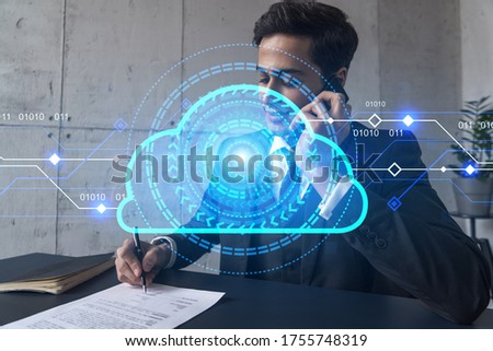 A man in office signing papers while talking phone and cloud concept hologram. Double exposure. Formal wear.