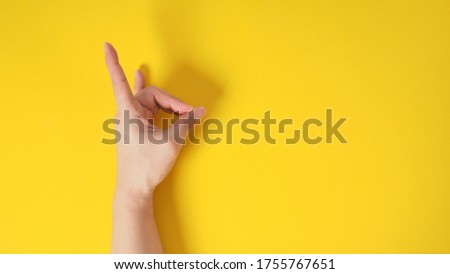 Male model is doing "Devil's horns" hand sign  on yellow blackground.