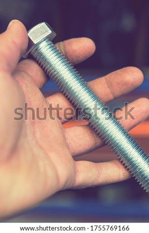hand holds an iron bolt. repair concept. close-up. vertical photo