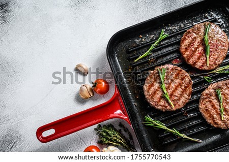 Beef burger patties sizzling on a hot barbecue pan. White background. Top view. Copy space