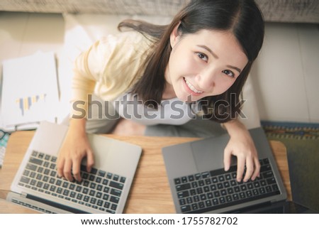 A woman's hand on the computer Top view of laptop notebook in girl's hands sitting on a wooden floor with coffee, work from home or cafe
