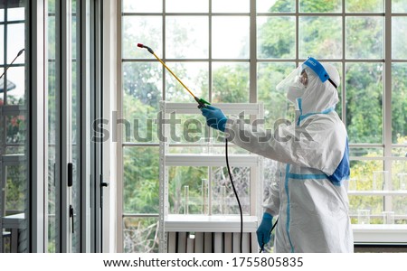 worker from decontamination services wearing personal protective equipment or ppe including suit, face shield and mask. He uses disinfectant to spray and clean scientist lab Royalty-Free Stock Photo #1755805835