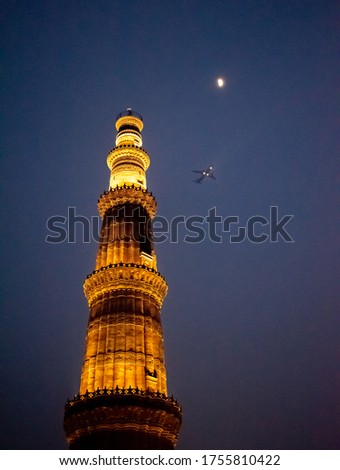 A plane flying past the Qutub Minar at night, Delhi, India