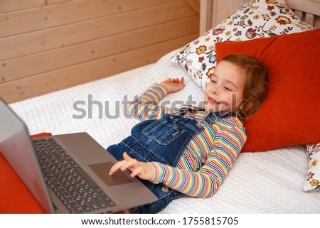 A little girl looks at the computer with different emotions. Girl plays on a computer