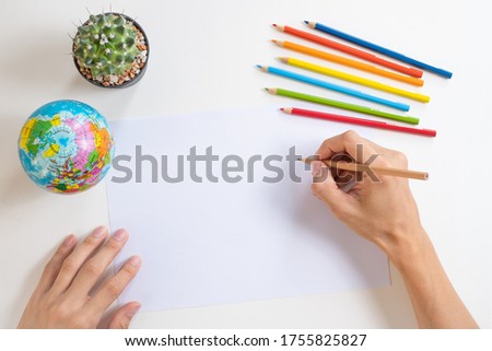 Top view of drawing or coloring picture with cactus and globe model on white table