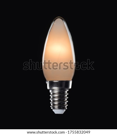 Lit image of a warm white candle bulb with E14 holder on a black background Royalty-Free Stock Photo #1755832049