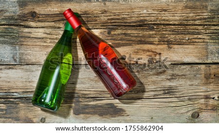 Mockup photo of two magnum bottles of rosé and white wine with green and red caps lying on some weathered vintage rusty wooden boards. 