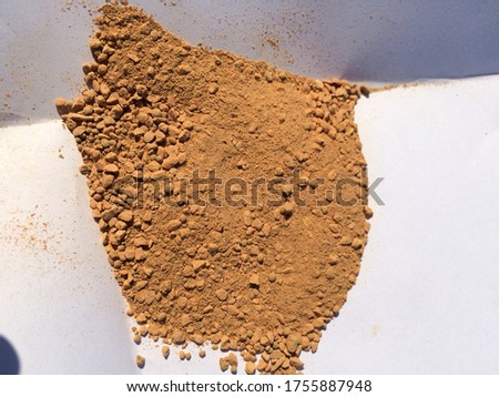 grains of brown sand on white paper, small crushed ceramics, a component for preparing masonry mortar for construction works made of bricks