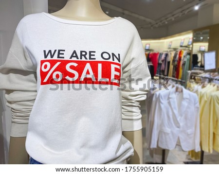 Mannequin wearing white sweaters with red inscription WE ARE ON SALE at shopping mall - seasonal sale or Black Friday concept