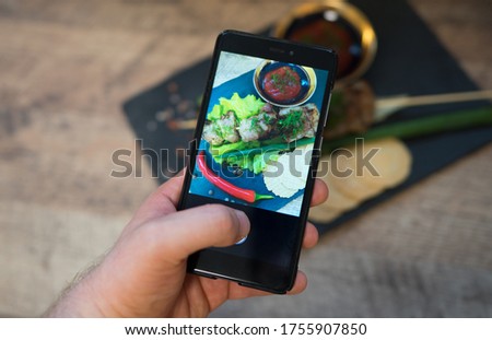 Woman doing photo of shashlik on mobile phone.