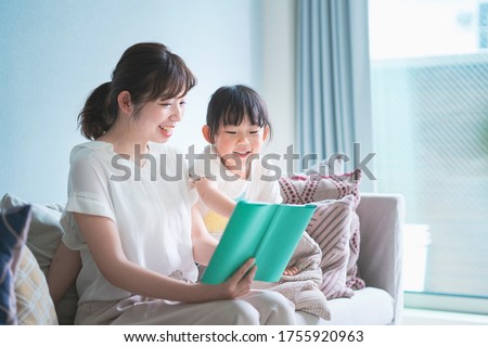 Mother and daughter sitting on the sofa and reading a picture book