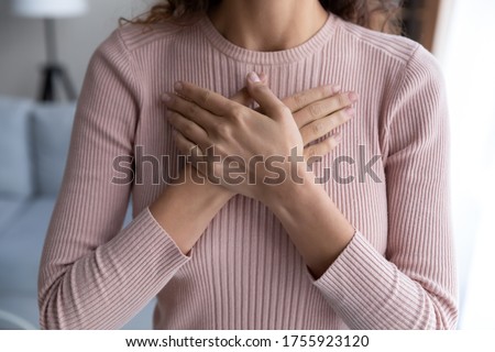 Close up hopeful grateful woman keeping hands on chest, dreamy young female thanking god and faith, feeling love, gratitude, appreciation, thinking dreaming about good future, making wish Royalty-Free Stock Photo #1755923120