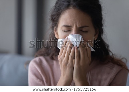 Close up unhealthy exhausted woman blowing nose, holding white paper tissue handkerchief, sick young female sneezing, suffering from symptom of chronic sinusitis, cold or flu, seasonal allergy Royalty-Free Stock Photo #1755923156