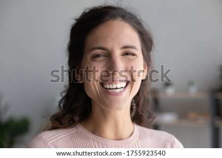 Head shot portrait close up laughing overjoyed beautiful woman with toothy smile looking at camera, making video call to friends or relatives, excited young female blogger recording vlog