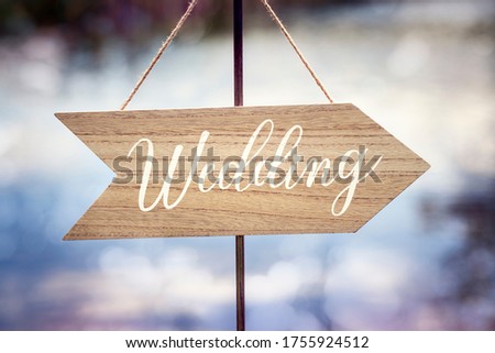 Wedding ceremony wooden arrow location sign with lake reflection background